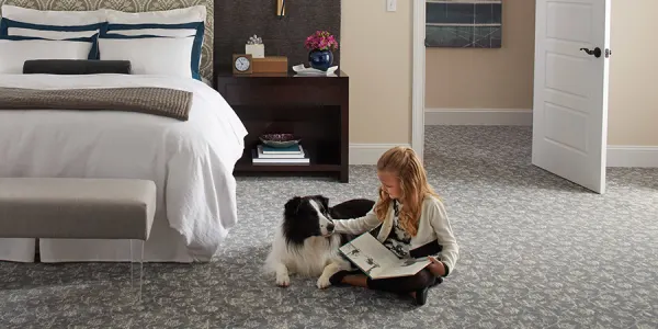 Girl sitting on plush carpet petting a dog